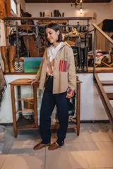 Sobre camisa beige de manga larga, con bolsillos frontales y detalles de tela guardada multicolor en bolsillos y puños.