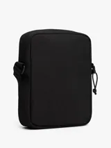 Cartera reporter de estilo urbano color negro, con compartimento principal con cierre, cordones elásticos ajustables en el frente y correa ajustable. Presenta el logo de la marca en un parche frontal y etiqueta lateral de Cordura.