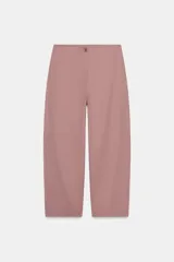 Pantalón de tiro alto color rosado, estilo ballon o culotte, con costuras diagonales marcadas en el frente y cierre frontal con botón y cremallera.