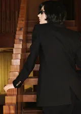 Chaqueta tipo blazer de doble botonadura en color negro, con solapas de muesca, bolsillos frontales con solapa y cierre de botones dorados. Presenta un diseño estructurado con forro interior.