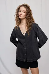 Campera de denim con diseño a rayas verticales y calce recto. Presenta escote en V, cierre frontal con botones metálicos y mangas largas.