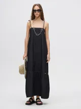 Vestido midi de denim color negro, con corte holgado, tirantes finos ajustables y falda con volado en el bajo.