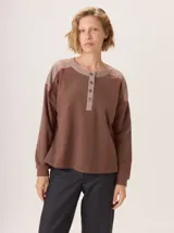 Buzo de manga larga con diseño color block. Cuerpo principal color camel, sección central de la espalda color azul marino liso y hombros con tejido de lana texturado en tonos azules. Posee un parche de cuero marrón con el logo grabado en la espalda.