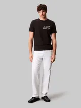 Remera de algodón negro con cuello redondo y mangas cortas. Presenta un diseño gráfico con el logo de la marca estampado en el pecho en color blanco y amarillo.