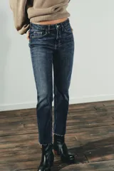 Jeans de tiro alto color marrón oscuro con acabado lavado, corte recto/flare y bajo cropped sin costuras. Presenta cinco bolsillos y cierre frontal con cremallera y botón metálico.