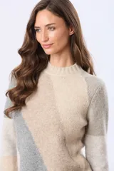 Buzo tejido de punto con diseño de bloques de color en diagonal en tonos beige, gris y rosado. Presenta cuello redondo, manga larga y terminaciones acanaladas en cuello, puños y cintura.