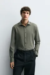 Camisa de corte regular fit color celeste, confeccionada en tejido fácil de planchar. Cuenta con cuello italiano abierto, manga larga con puño abotonado y cierre frontal con botonadura.