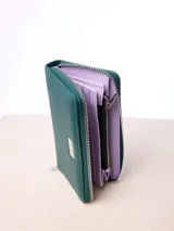 Billetera Rusty modelo Novadi W26 de color verde oscuro, con cierre perimetral y placa metálica frontal con el logo de la marca.