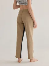 Pantalón cigarette color beige, de denim con costuras visibles, pretina trasera elástica y bolsillos delanteros y traseros.