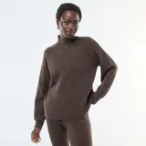 Sweater de punto canalé en color marrón, con cuello alto y mangas largas con puños ajustados. Presenta un diseño de corte holgado y tejido texturizado.