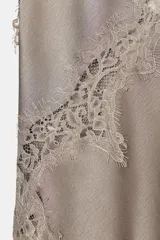 Top lencero negro de escote pico y tirantes finos. Presenta aplicación de encaje a tono en el escote y el bajo asimétrico.