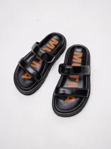 Sandalias de cuero vacuno color marrón con acabado brillante, diseño de dos tiras anchas acolchadas y plataforma baja.