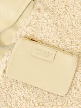 Cartera tipo hobo de gran tamaño, con forma envolvente y asa integrada. Presenta un diseño bicolor y de texturas mixtas: una sección es de cuero negro texturizado y la otra de material afelpado negro (tipo borrego o sherpa).