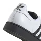 Championes Adidas Superstar de diseño clásico, con exterior de cuero blanco, icónicas tres tiras laterales en negro, puntera de goma reforzada y suela de plataforma en color negro.