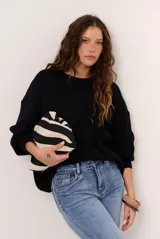 Buzo de punto negro, de corte holgado, con mangas largas y cuello redondo.