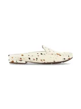 Zueco destalonado de cuero con pelo, diseño tipo mocasín abierto con estampa de animal print tipo vaca en tonos blanco, marrón y negro, y suela plana de goma.