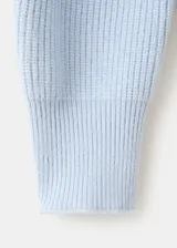 Jersey de punto celeste con cuello polo, escote en V y mangas largas con puños ajustados.