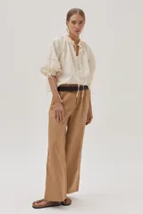 Blusa color crudo con bordado calado, cuello con volantes y lazos para ajustar. Mangas abullonadas con puños elásticos y lazos.