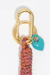 Llavero con cuerpo de cabo trenzado multicolor, mosquetón y argolla metálicos dorados, dije de corazón esmaltado en color turquesa y dijes metálicos dorados que forman la palabra LOVE.