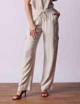 Pantalón cargo de lino a rayas verticales grises y blancas, marca Marissa Olivia. Pretina ancha elastizada con lazo de ajuste, bolsillos inclinados delanteros y bolsillos laterales con botón.