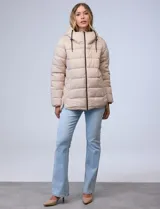 Campera puffer color marrón con capitoneado horizontal. Tiene cuello alto y capucha ajustable con cordones, con el interior del cuello en textura aterciopelada negra. Cierre frontal completo y bolsillos laterales. El corte es ligeramente más largo en la parte posterior con aberturas laterales redondeadas.