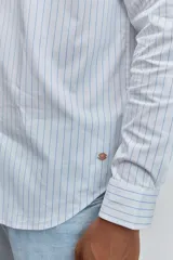 Camisa de manga larga con cuello clásico y cierre frontal de botones. Presenta un diseño de rayas verticales finas en tonos claros.