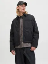 Campera estilo worker de color negro, con cuello camisero, cierre frontal con cremallera y bolsillos laterales. Presenta un diseño minimalista y funcional con acabado limpio.