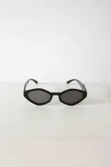 Lentes de sol con silueta geométrica y angular de estilo cat-eye hexagonal, armazón negro y cristales oscuros con protección UV400.