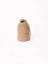 Championes de plataforma baja de color beige, con cordones tono sobre tono y detalle de placa metálica en los cordones.