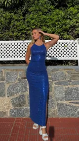 Vestido largo de fiesta azul eléctrico con lentejuelas, corte ajustado, escote halter y abertura lateral en la falda.