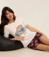 Conjunto de pijama compuesto por una remera de manga corta color crema con estampa frontal de Stitch y un short color bordó con estampado integral de Stitch. Ambas prendas están confeccionadas en viscosa con elastano.