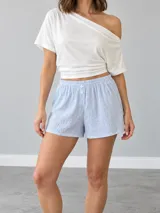 Short celeste a rayas finas blancas, de corte fluido, con cintura elástica fruncida y detalle de botones decorativos al frente.