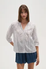 Camisa de algodón con diseño de rayas verticales y detalles bordados. Presenta cuello en V, cierre frontal con botones y mangas tres cuartos con terminación elástica.