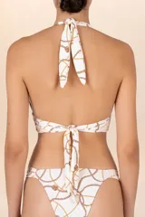Top de traje de baño halter blanco con estampado de cadenas doradas y marrones, con faja amplia que realza el escote. Se ata al cuello y a la espalda con tiras anchas.