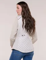 Chaleco acolchado de diseño entallado color beige, con matelaseado en patrón de rombos en frente y espalda, cuello alto estructurado y cierre frontal completo con cremallera metálica y ribete a contraste.