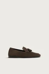 Mocasines de vestir para hombre confeccionados en piel con acabado en gamuza de color marrón, con detalle de borlas en el empeine y suela plana con ligero tacón.