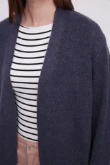 Saco abierto de punto, color gris claro, con diseño holgado y mangas largas.