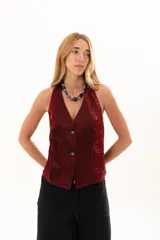 Chaleco de corte sastrero en color bordó, con acabado satinado y textura arrugada. Presenta escote en V profundo, cierre frontal con botones y diseño sin mangas.
