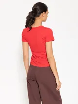 Remera blanca de algodón pima y elastano, corte ajustado, manga corta, cuello redondo y largo hasta la primera cadera.