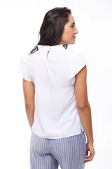 Blusa blanca de poliéster con cuello redondo y mangas cortas con volados.