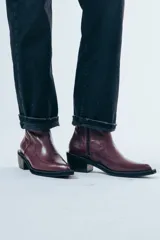 Bota de caña media confeccionada en cuero negro con acabado brillante, diseño de silueta limpia, puntera cuadrada y taco cuadrado de altura media.