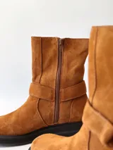 Bota corta de cuero color camel, con correa decorativa alrededor del tobillo y suela de goma negra.