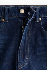 Jean de tiro alto con corte wide leg, confeccionado en denim rígido de color azul oscuro. Presenta diseño de cinco bolsillos, cierre con botón y ruedo deshilachado.