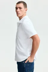 Remera polo blanca de manga corta en piqué de algodón, con cuello clásico y tapeta de dos botones.