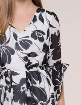 Vestido corto de gasa semitraslúcida con estampado floral en blanco y negro, escote en V, mangas tres cuartos con volantes y lazo ajustable en la cintura.