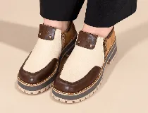 Zapatos de cuero con diseño tricolor en tonos marrón, tostado y marfil, con plataforma y suela dentada. Cuenta con cierre lateral y costuras decorativas.