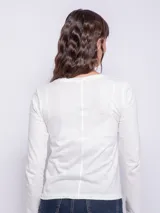 Remera blanca de manga larga con cuello redondo y frunces verticales en el centro.