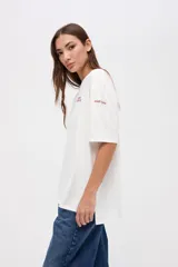 Remera de manga corta color azul, con calce clásico y tajos laterales. Presenta un bordado pequeño en el pecho con el texto 'UNIFORM STUDIO LAB' y un detalle bordado en la manga. Confeccionada en algodón lavado con textura suave.