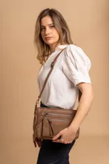 Bandolera de tamaño mediano confeccionada en símil cuero con detalles en nobuck. Presenta un diseño rectangular con cierre principal, bolsillos frontales con cierre y correa larga ajustable para llevar al hombro o cruzada.