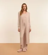 Conjunto de pijama de tres piezas confeccionado en tricot, compuesto por una blusa de cuello redondo, un pantalón de corte recto con cintura elástica y una bata larga abierta. Presenta una textura suave y fluida en color beige.
